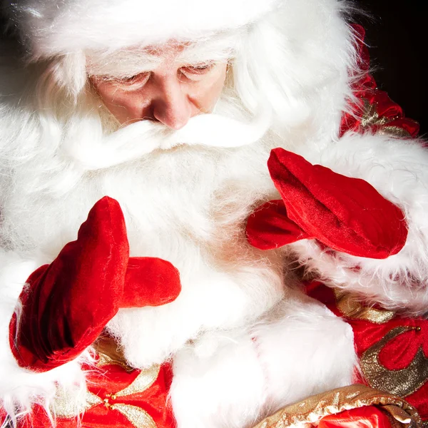Santa sitter vid jul rum och tittar in i säcken — Stockfoto