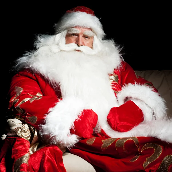 Père Noël assis avec un sac à l'intérieur à la chambre de nuit sombre — Photo