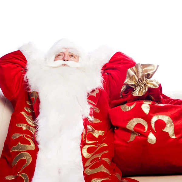 Traditionella jultomten vila på soffan inomhus och dagdrömmer. — Stockfoto