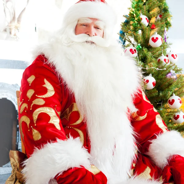 Santa κάθεται στο χριστουγεννιάτικο δέντρο, τζάκι και κοιτάζοντας ca — Φωτογραφία Αρχείου