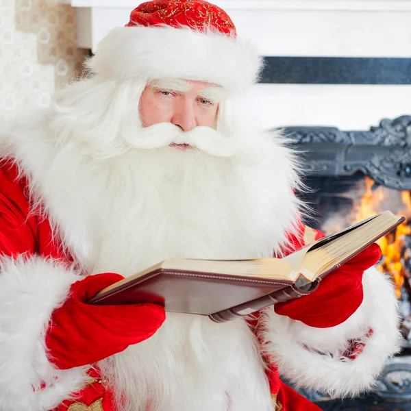 산타 크리스마스 나무에 앉아 벽난로 부를 읽고 — 스톡 사진