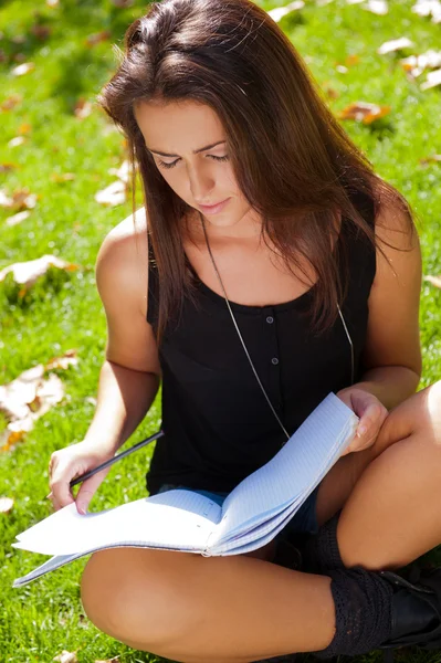 Retrato de uma bela jovem estudante sentada ao ar livre em — Fotografia de Stock