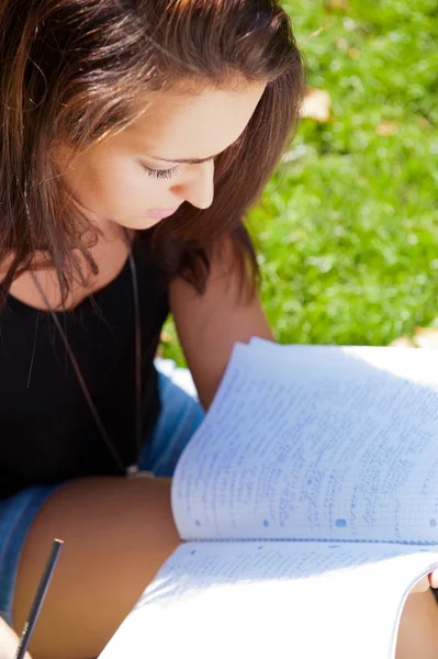Retrato de uma bela jovem estudante sentada ao ar livre em — Fotografia de Stock