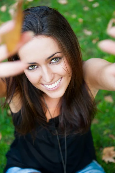 Porträtt av leende ung flicka sitter på gräset i skogen en — Stockfoto