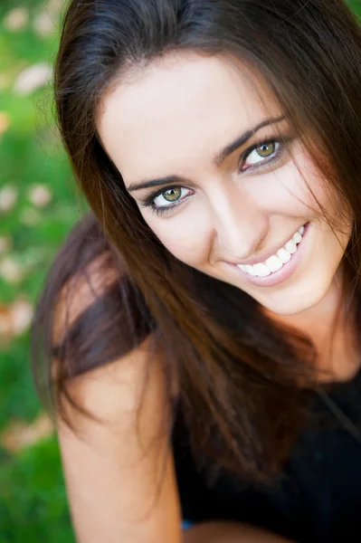 Портрет улыбающейся девушки, сидящей на траве в лесу и — стоковое фото