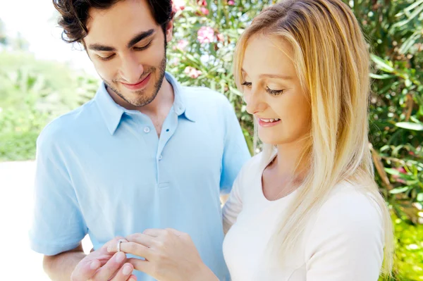 Happy young hispanic man gifting a ring to a beautiful surprised — Stock Photo, Image