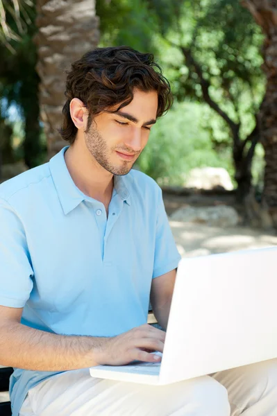 Retrato de um jovem com laptop ao ar livre sentado no banco — Fotografia de Stock