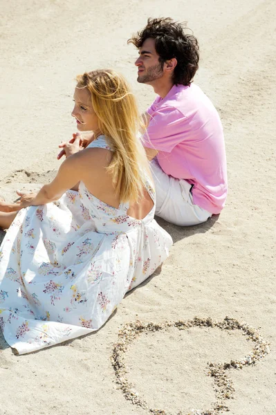 Πορτρέτο του νεαρό ζευγάρι, κάθονται μαζί στην άμμο στην παραλία και l — Φωτογραφία Αρχείου