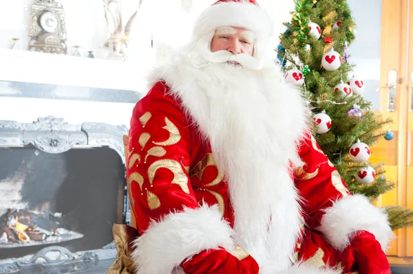 Santa sentado en el árbol de Navidad, chimenea y mirando a ca — Foto de Stock