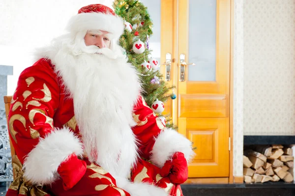 Santa κάθεται στο χριστουγεννιάτικο δέντρο, τζάκι και κοιτάζοντας ca — Φωτογραφία Αρχείου