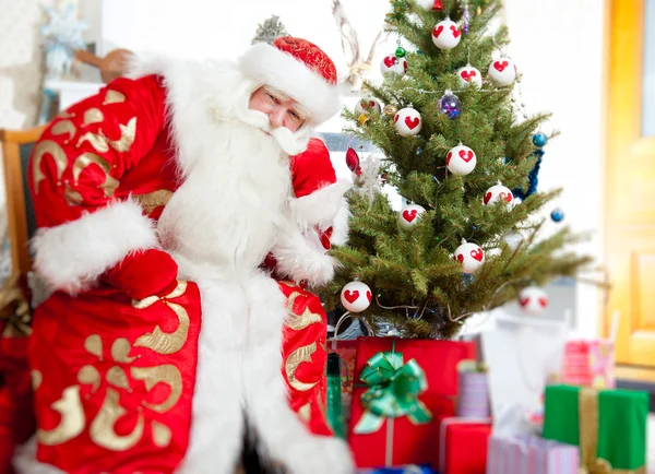 Santa sentado na árvore de Natal, lareira e olhando para ca — Fotografia de Stock