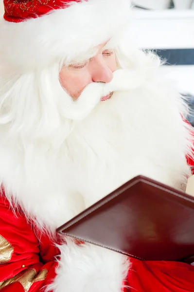 Santa sitting at the Christmas tree, fireplace and reading a boo — Stock Photo, Image