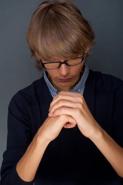 Młody człowiek modli się na szarym tle — Zdjęcie stockowe