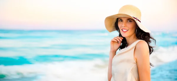Sonriente mujer joven con un sombrero de paja y divertirse en el be — Foto de Stock