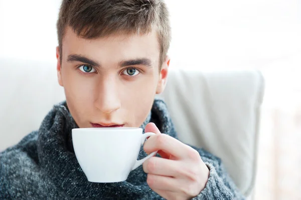 Портрет молодого человека, пьющего кофе, сидящего на армчае — стоковое фото