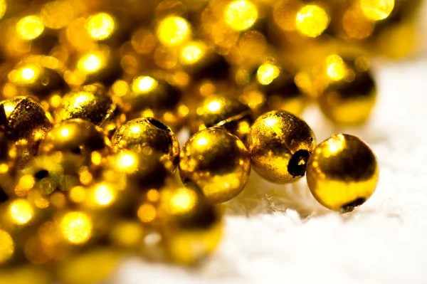 Perline di plastica dorata su bianco — Foto Stock