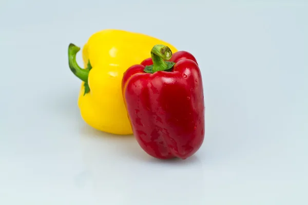 Red and yellow capsicums on bluish background — Stock Photo, Image