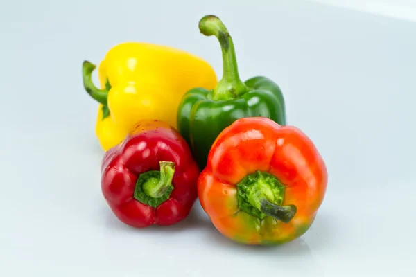 Vier Paprika auf bläulicher Oberfläche — Stockfoto