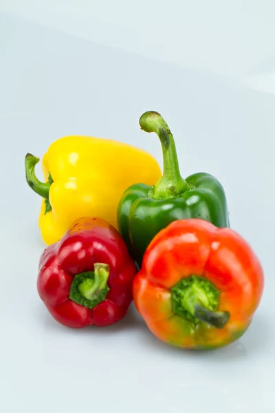 Four capsicums on bluish surface II — Stock Photo, Image