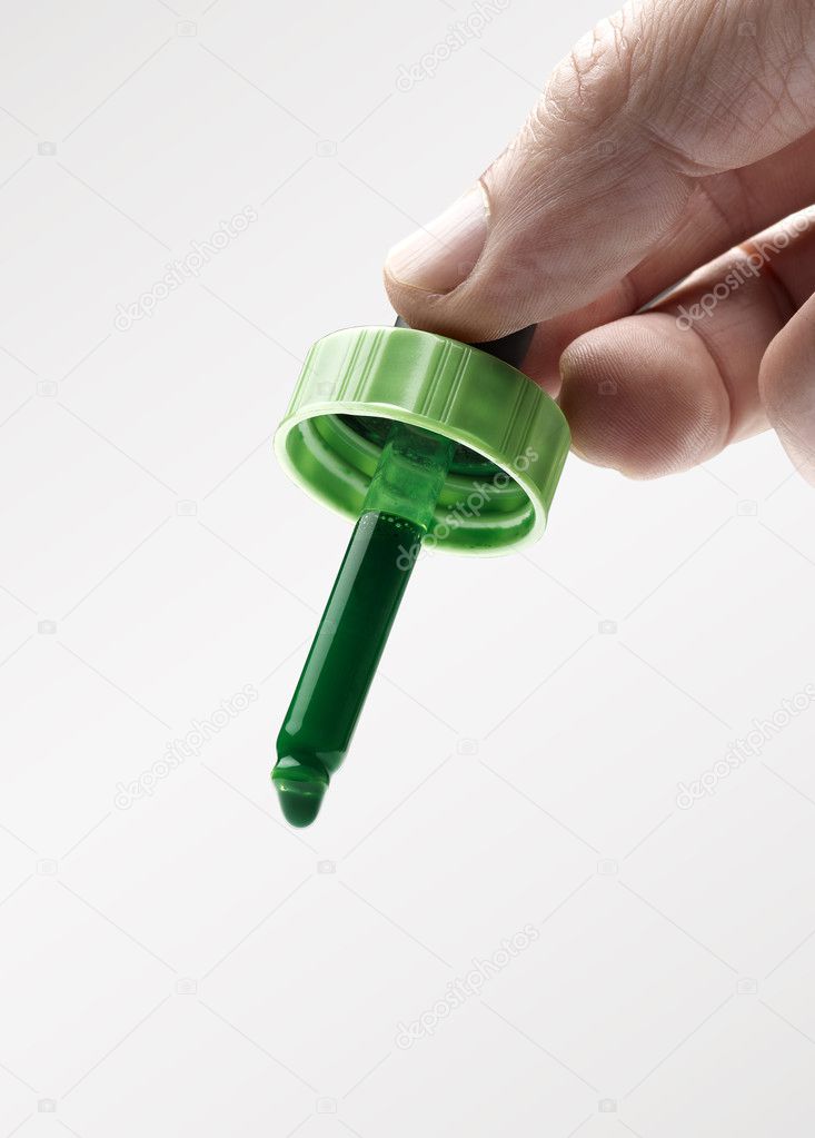 Man's hand holding an eyerdropper with green ink