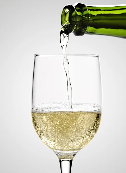 Vinho de champanhe branco sendo derramado em um copo em branco — Fotografia de Stock