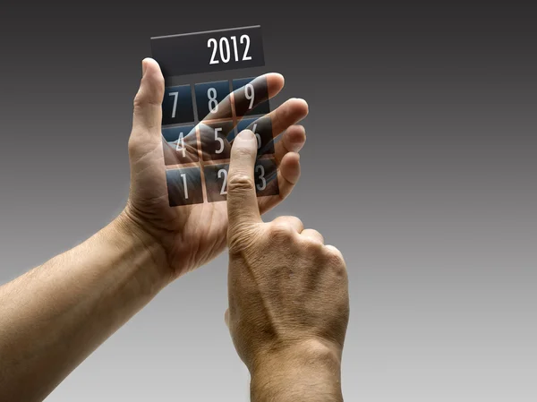 Duas mãos segurando uma calculadora com 2012 incluído — Fotografia de Stock