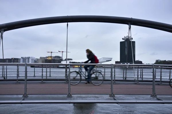 Holanda, Amsterdam, ciclista en un puente cerca de la Estación Central — Foto de Stock