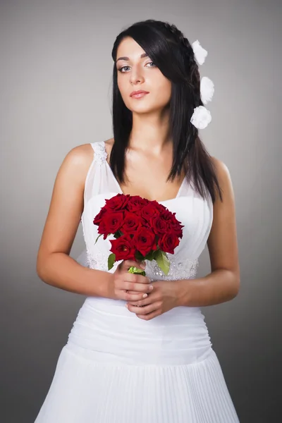 Stüdyoda çiçeklerle düğün kıyafeti giymiş güzel esmer gelin — Stok fotoğraf
