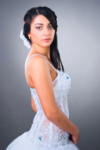 Joven novia morena vistiendo vestido de novia en estudio neutral bac —  Fotos de Stock