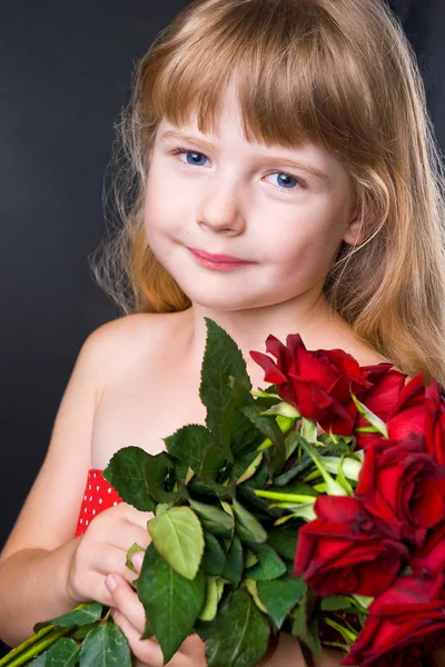 Entzückendes Mädchen mit einem Strauß roter Rosen auf dem schwarzen Hintergrund des Studios — Stockfoto
