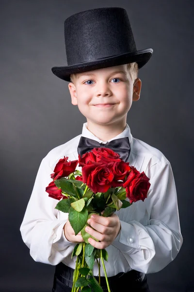 Stilig pojke bär klassiska kostym med blommor i händerna — Stockfoto