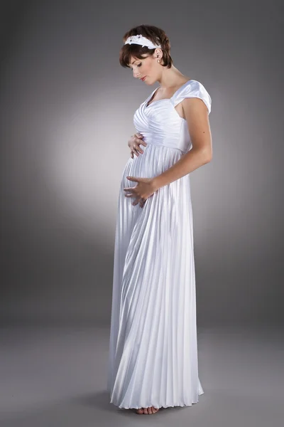 Beautiful pregnant bride wearing wedding dress on studio neutral background — Stock Photo, Image