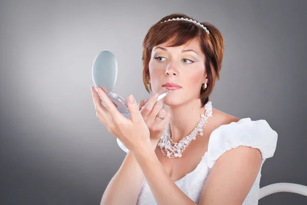 Young bride is doing makeup on studio neutral background — Stock Photo, Image