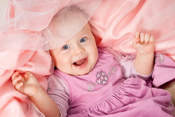 Glad spädbarn flicka avkopplande på rosa slöja — Stockfoto
