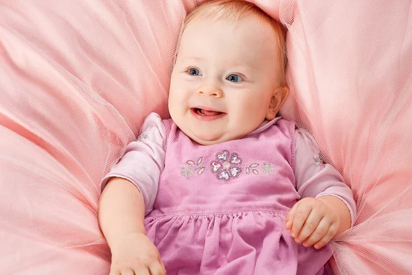 Mutlu bebek kız pembe perde üzerinde rahatlatıcı — Stok fotoğraf