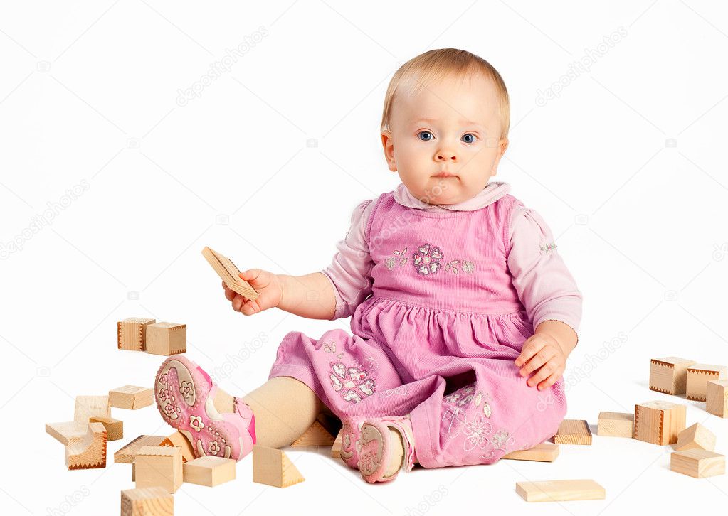 Infant girl playing with wooden blocks isolated on white background