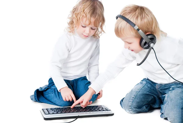 Duas crianças brincando com computador no chão isolado em fundo branco — Fotografia de Stock