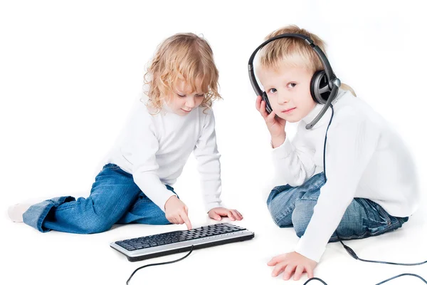 Dos niños jugando con el ordenador en el suelo aislado sobre fondo blanco —  Fotos de Stock