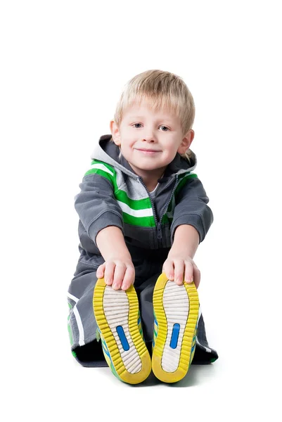 Beyaz arka plan üzerinde izole katta oturan sevimli sportif çocuk egzersiz — Stok fotoğraf