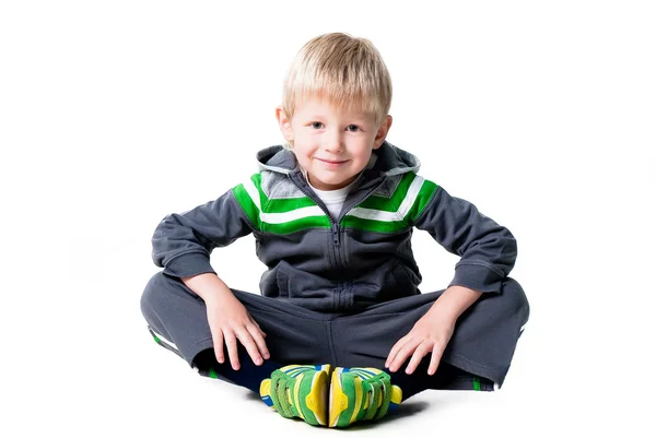 Niño deportivo feliz sentado en el suelo aislado sobre fondo blanco —  Fotos de Stock