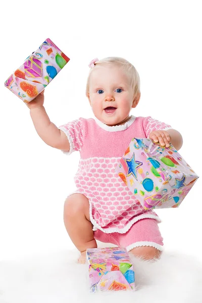 Happy infant girl sitting with gift boxes isolated on white background — Stock Photo, Image