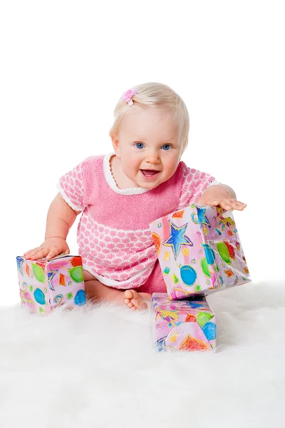 Happy infant girl sitting with gift boxes on white background — Stock Photo, Image