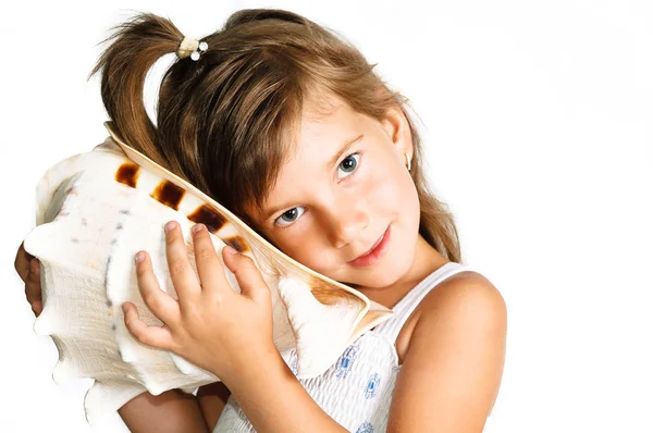 Χαριτωμένο μικρό girle ακούει ένα τεράστιο κοχύλι που απομονώνονται σε λευκό — Φωτογραφία Αρχείου