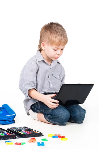 Slimme kleine jongen met computer en school supplies geïsoleerd op wit Stockafbeelding