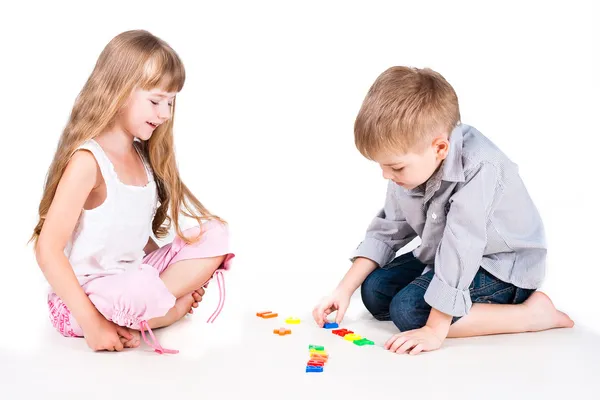 Δύο παιδιά παίζοντας με το αλφάβητο που απομονώνονται σε λευκό φόντο Εικόνα Αρχείου