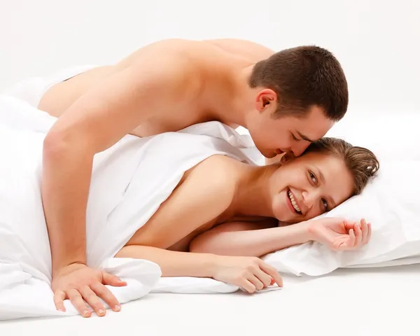 Homem inclinado sobre a mulher sorridente na cama — Fotografia de Stock