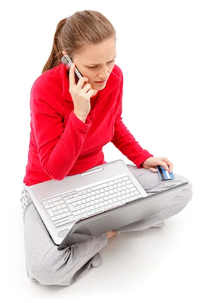Девушка разговаривает по телефону с ноутбуком на коленях — стоковое фото