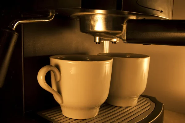 Καφετιέρα ρίχνει ζεστό καφέ espresso σε δύο φλιτζάνια. διάλειμμα σας! — Φωτογραφία Αρχείου
