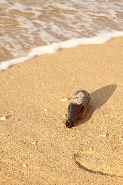 Macchiato aiuto sabbia bottiglia aperta sulla riva del mare . — Foto Stock