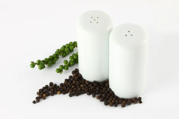 Pepper bottles and green black peppercorns. — Stock Photo, Image